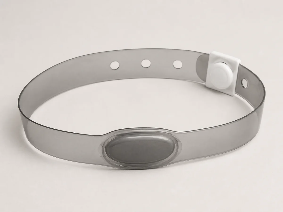 Smoke-grey vinyl RFID wristband with a heat-sealed oval capsule and snap closure