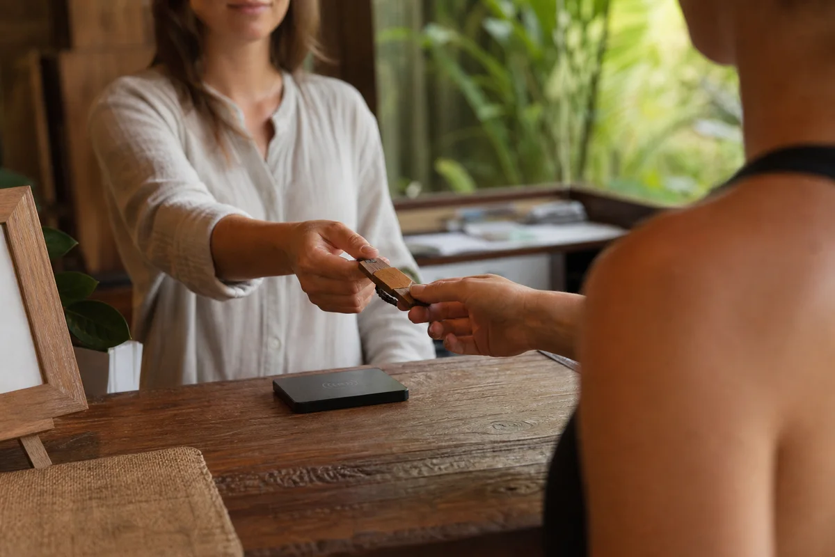Lodge receptionist handing a bamboo-and-cord RFID wristband to a guest